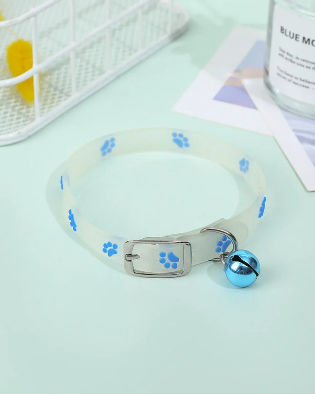 Luminous Cat Necklace with blue paw prints and bell on a light surface.