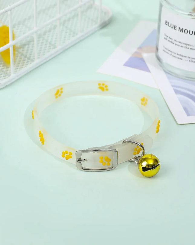 Luminous cat necklace with glowing silicone ring and bell on a light surface.